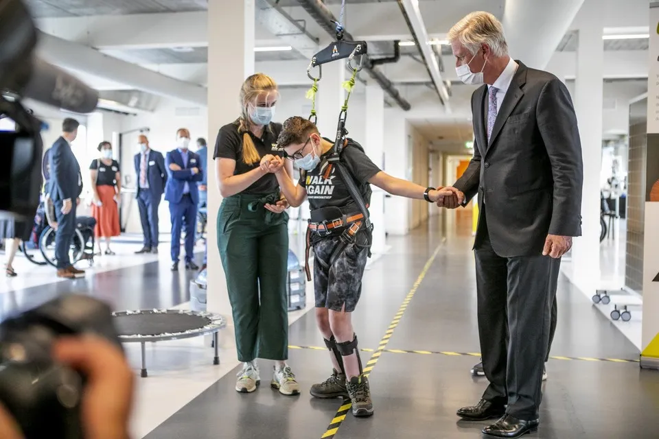 Een jongere leert opnieuw stappen, met steun van een begeleidster en een tilhulp